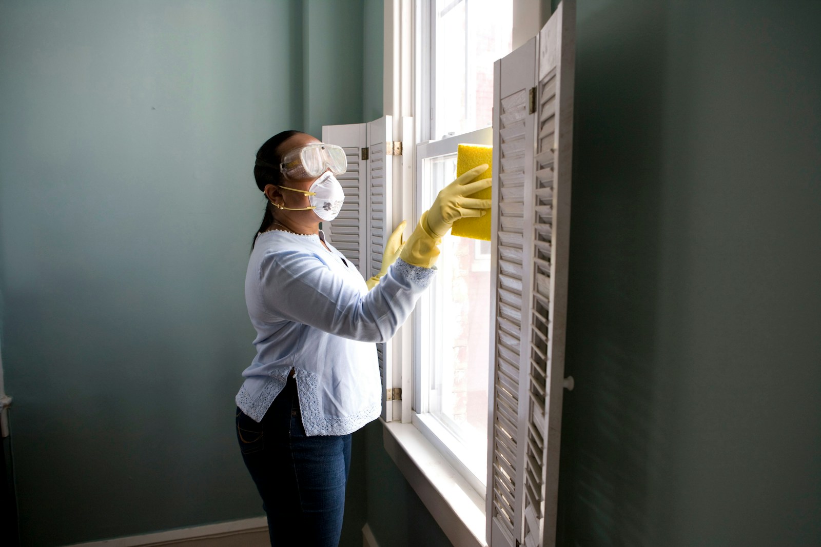 Photo by CDC woman in white long sleeve shirt and blue denim jeans standing beside white wooden framed glass